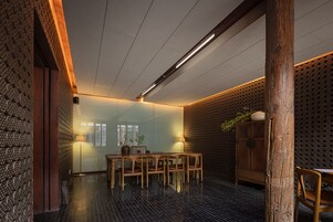 Un comedor con una mesa y sillas de madera, un aparador con una planta, y una pared con diseño.