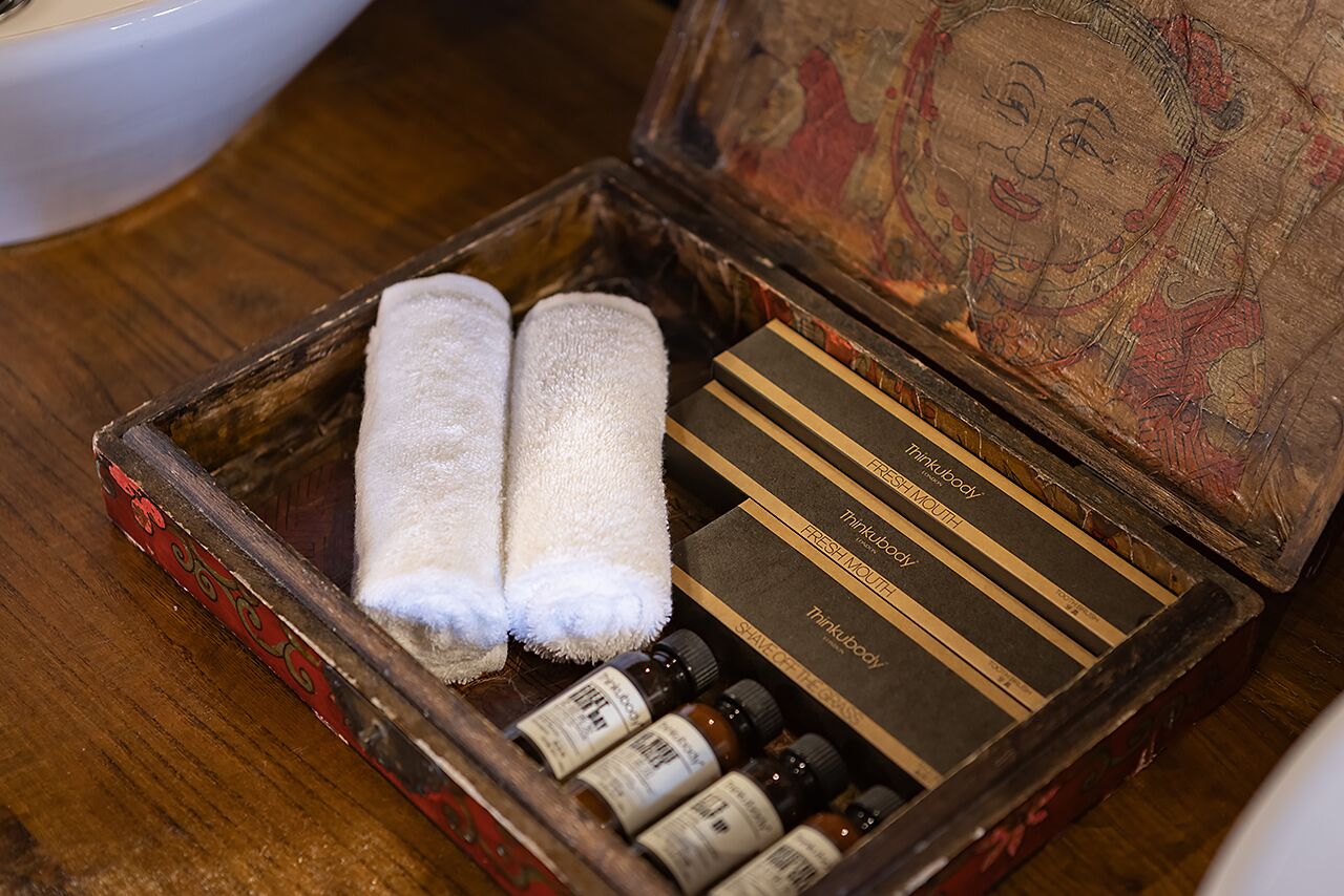 A wooden box with two white towels and several small bottles, likely containing toiletries, on a wooden surface.