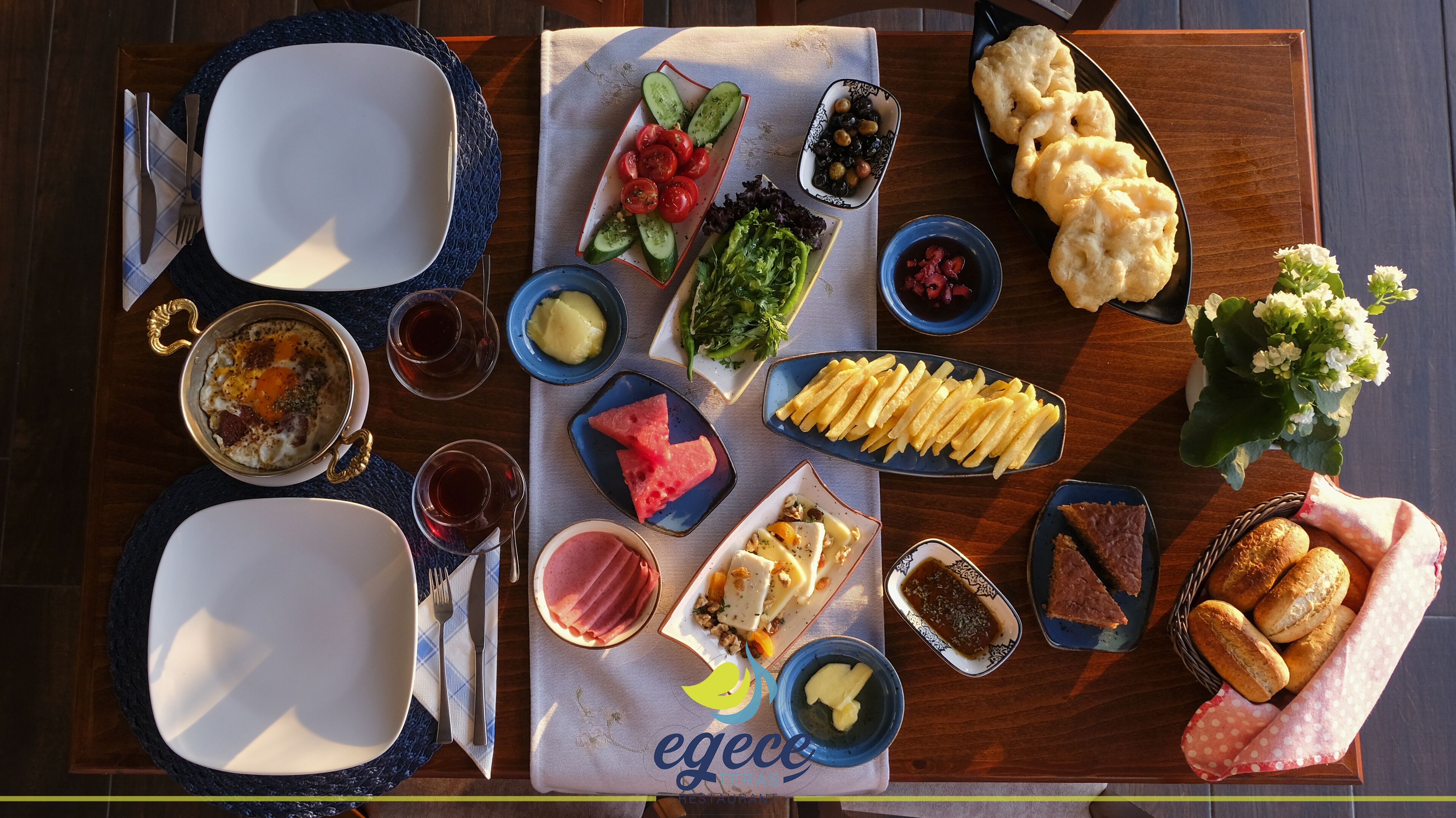 Ein Tisch, gedeckt für eine Mahlzeit mit verschiedenen Speisen, darunter ein Salat, Brot und ein Dessert.