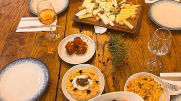 Una mesa de madera con varios platos, incluyendo un frutero, una bandeja de quesos y fuentes de comida.