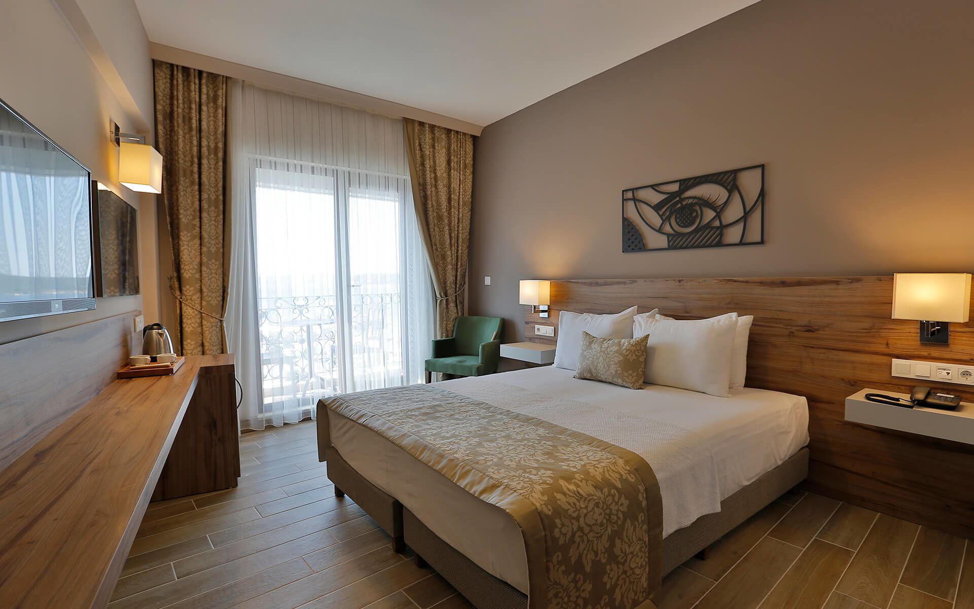 Habitación de hotel con una cama grande, un escritorio con lámpara, una silla y un cuadro en la pared.