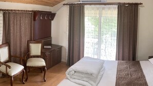 A room with a wooden ceiling, a bed with a white comforter, two upholstered chairs, a wooden desk, and a window with curtains. - Zarha Mountain Resort (Surmene)