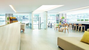A modern hotel lobby with a reception desk, seating area, and a view of the cityscape. - KritThai Residence (Bangkok)