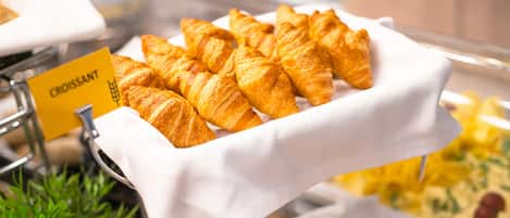 A buffet with croissants and other pastries.