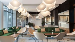 A modern lobby with green sofas, white chairs, and a central table. - Hampton by Hilton Lublin (Lublin)