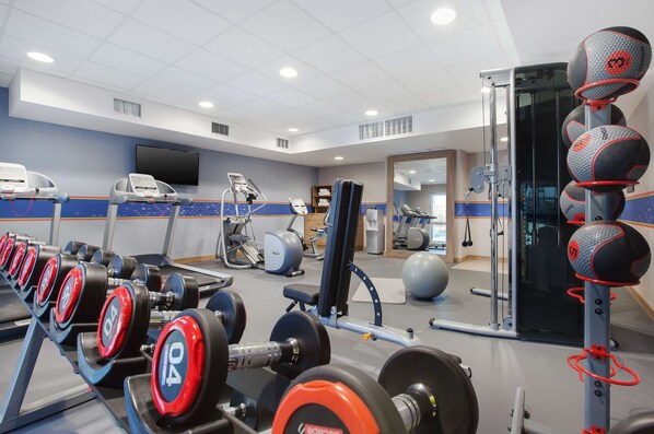 A gym with weightlifting equipment, treadmills, and exercise balls.