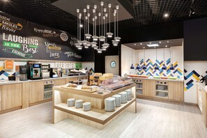 A modern kitchen area with a central island, a coffee station, and a wall with motivational quotes. - Hampton by Hilton Lublin (Lublin)