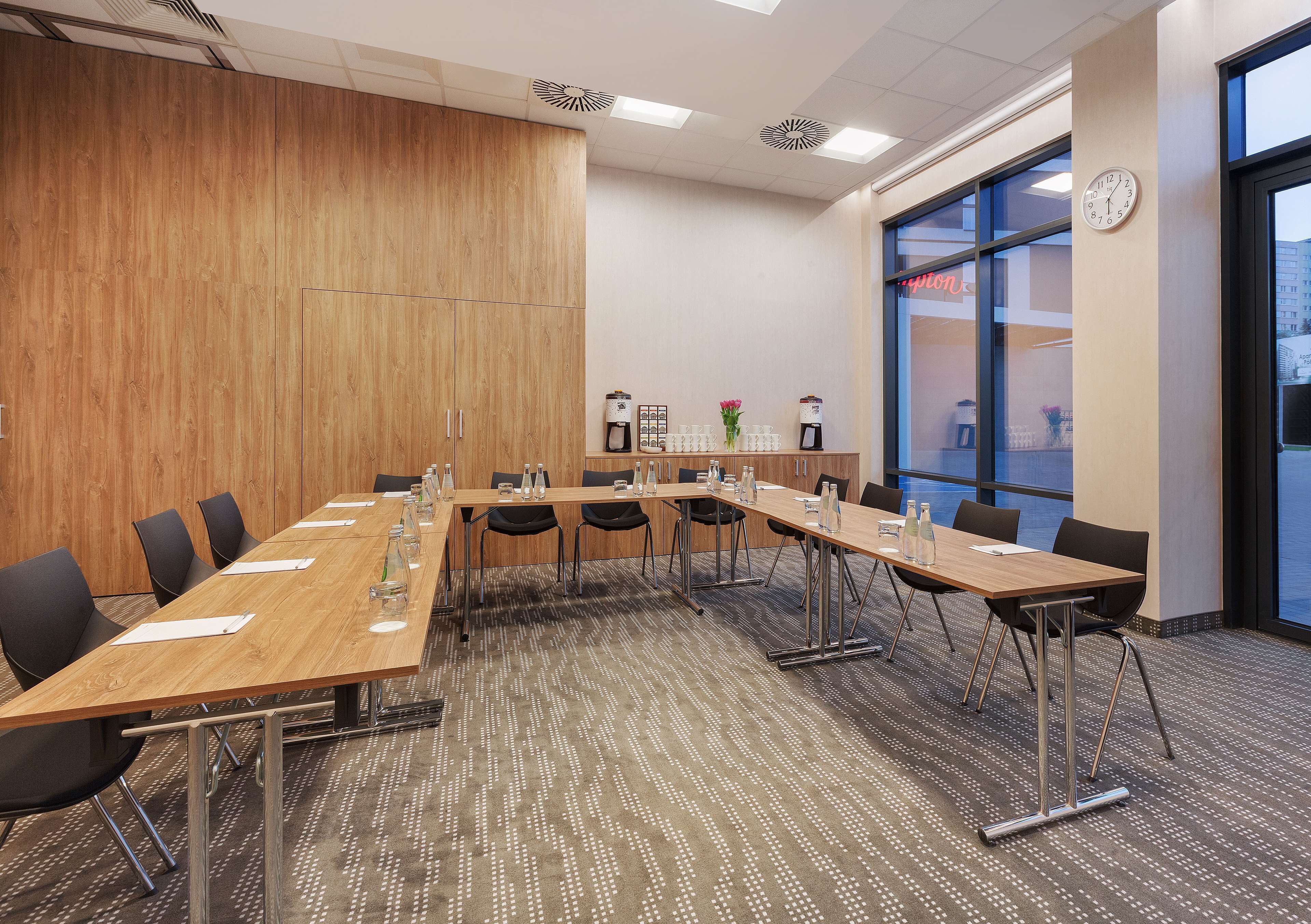 A conference room with a long table, chairs, and a clock on the wall.