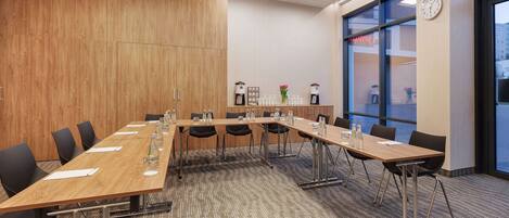A conference room with a long table, chairs, and a clock on the wall.