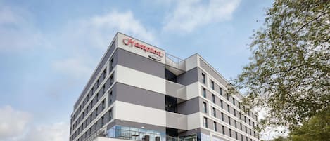 Un hotel moderno con techo plano, varios pisos y un letrero llamativo.