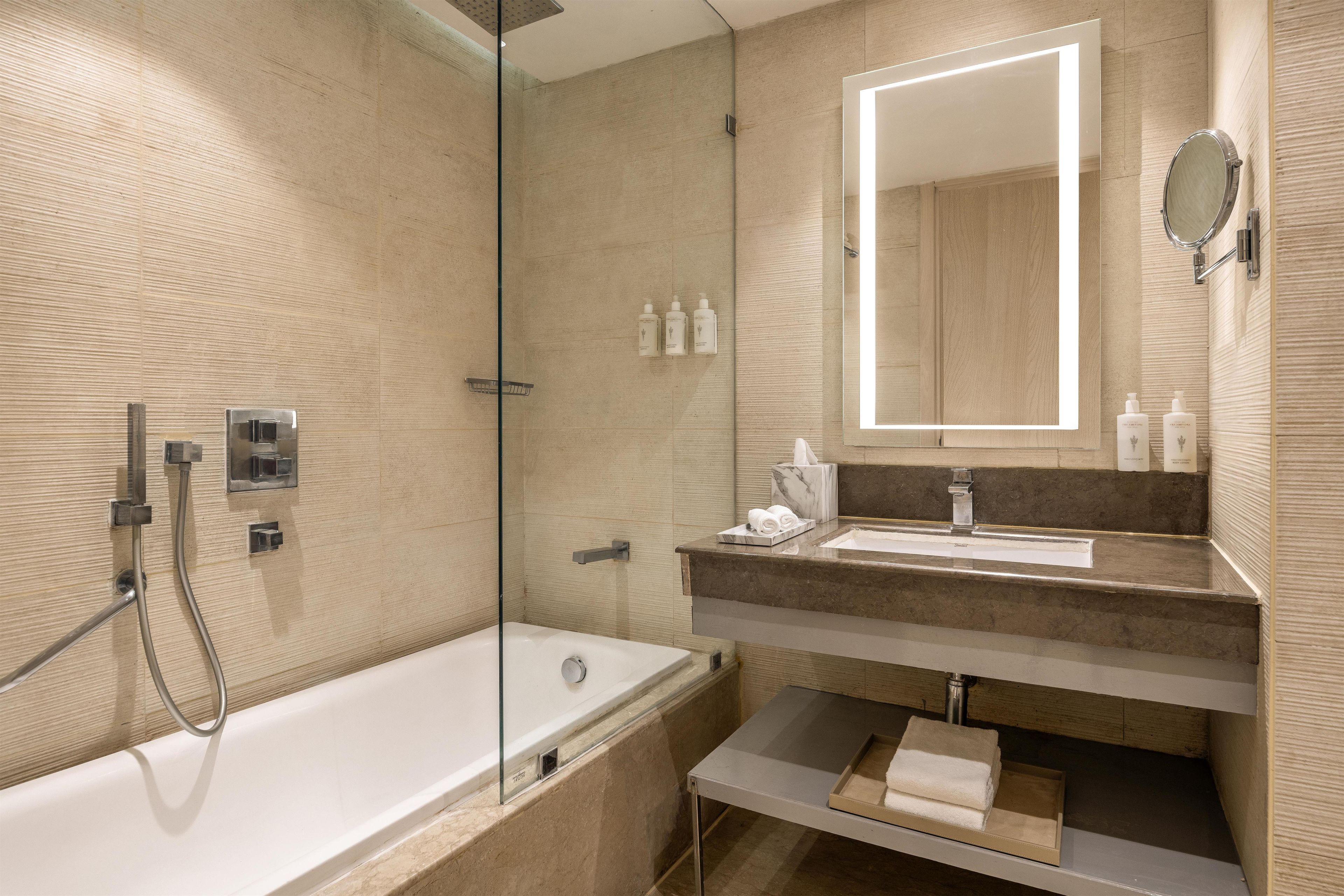 Un bagno moderno con cabina doccia in vetro, una vasca da bagno bianca e un mobile lavabo con piano in marmo.