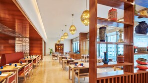 A modern restaurant with wooden decor, hanging lights, and a variety of colorful pottery displayed on shelves. - Hilton Garden Inn Lucknow (Lucknow)