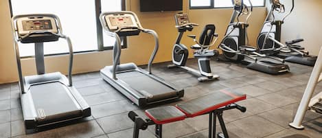 A gym with treadmills, elliptical machines, and weight benches.