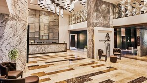 A spacious lobby with a marble reception desk, modern chandeliers, and a geometric wall design. - Hilton Garden Inn Lucknow (Lucknow)