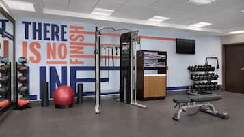 A gym with exercise equipment, a motivational wall, and a wall-mounted TV.