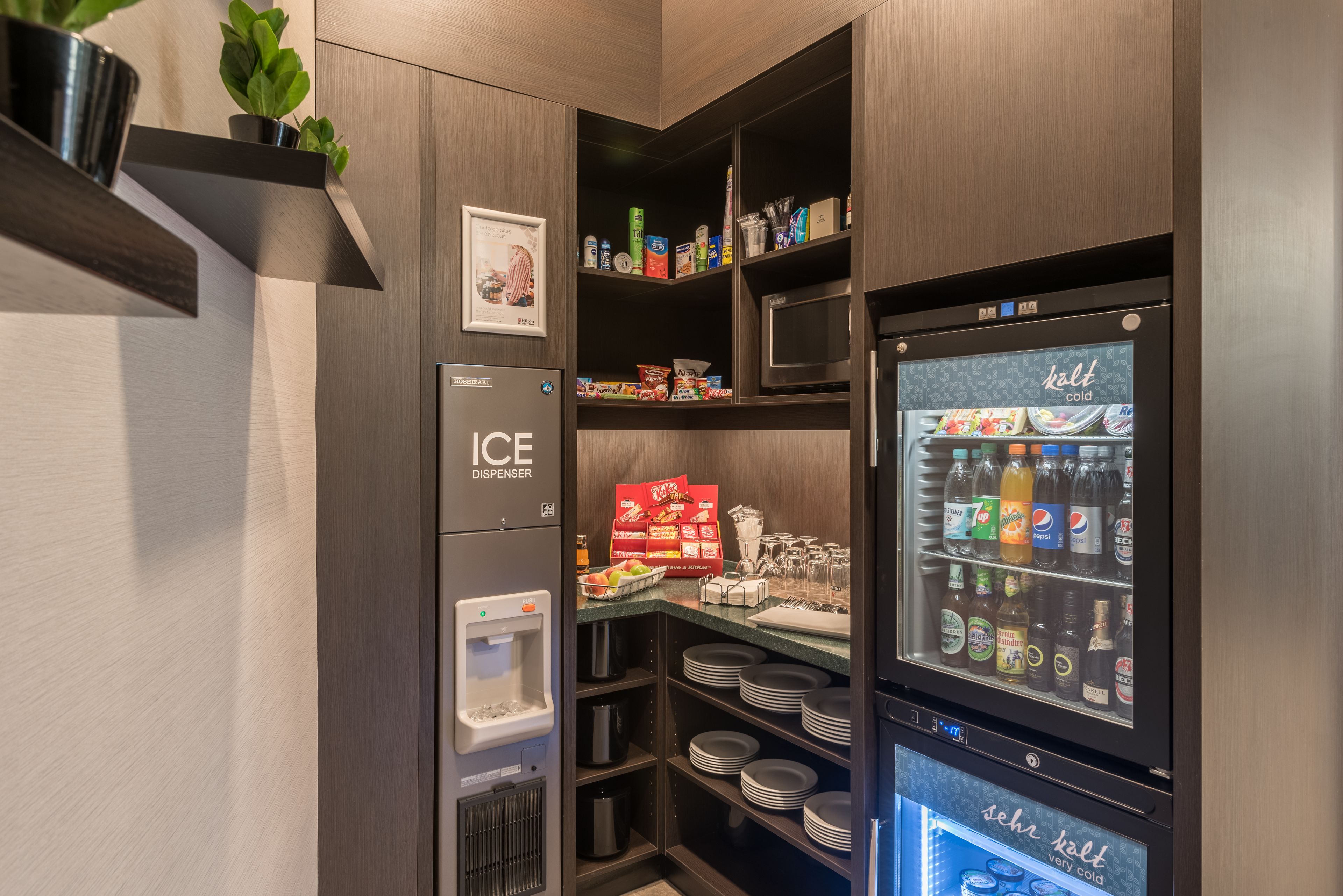 Un espacio de cocina compacto con dispensador de hielo integrado, microondas y dispensador de bebidas.