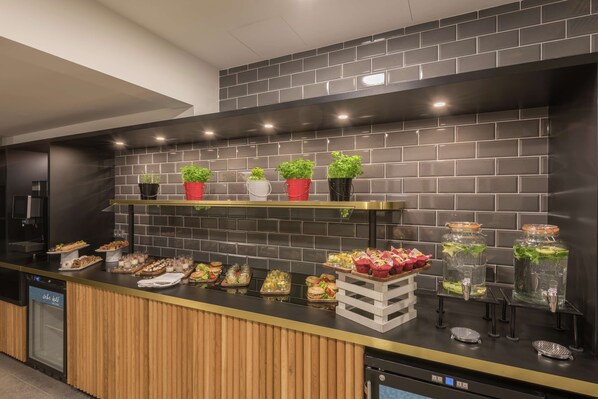 A modern kitchen with a black tiled backsplash, wooden counter, and various food items displayed.