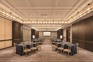 A conference room with multiple tables and chairs, a large screen, and a carpeted floor. - Hilton Fuzhou (Fuzhou)