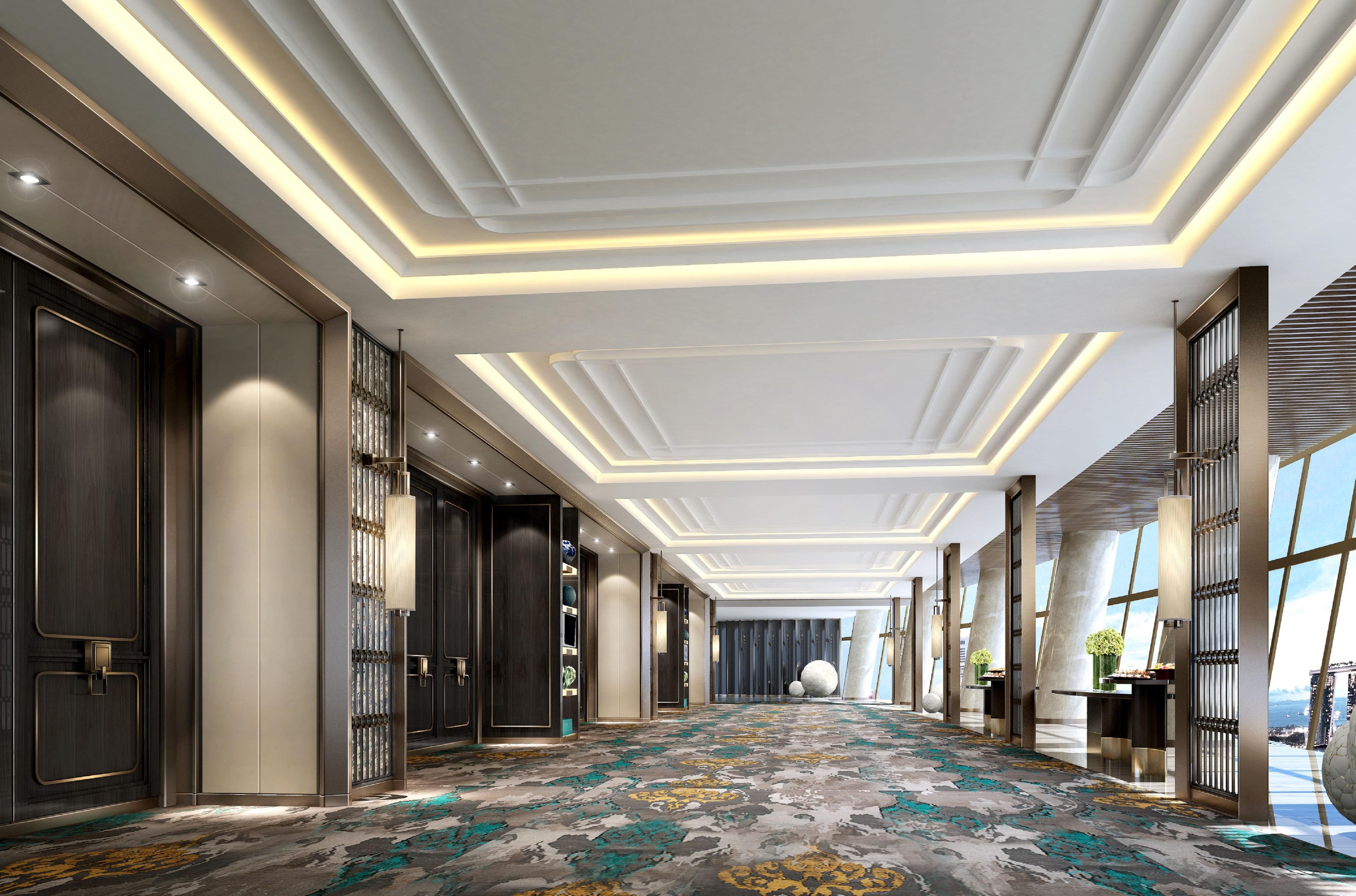 A hotel corridor with a patterned carpet, recessed lighting, and large windows.