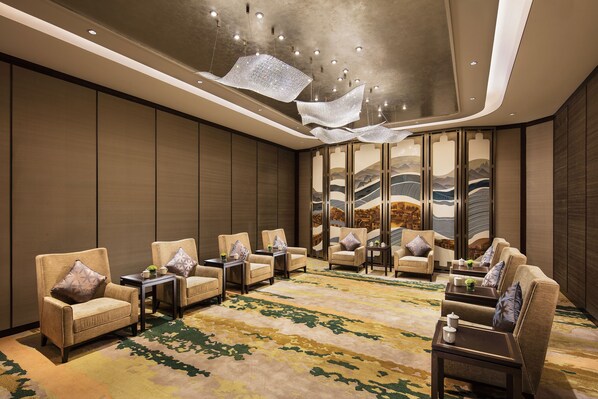 A spacious lobby with a modern design, featuring a large seating area with sofas and armchairs, a patterned carpet, and a large wall with a mural. - Hilton Fuzhou (Fuzhou)