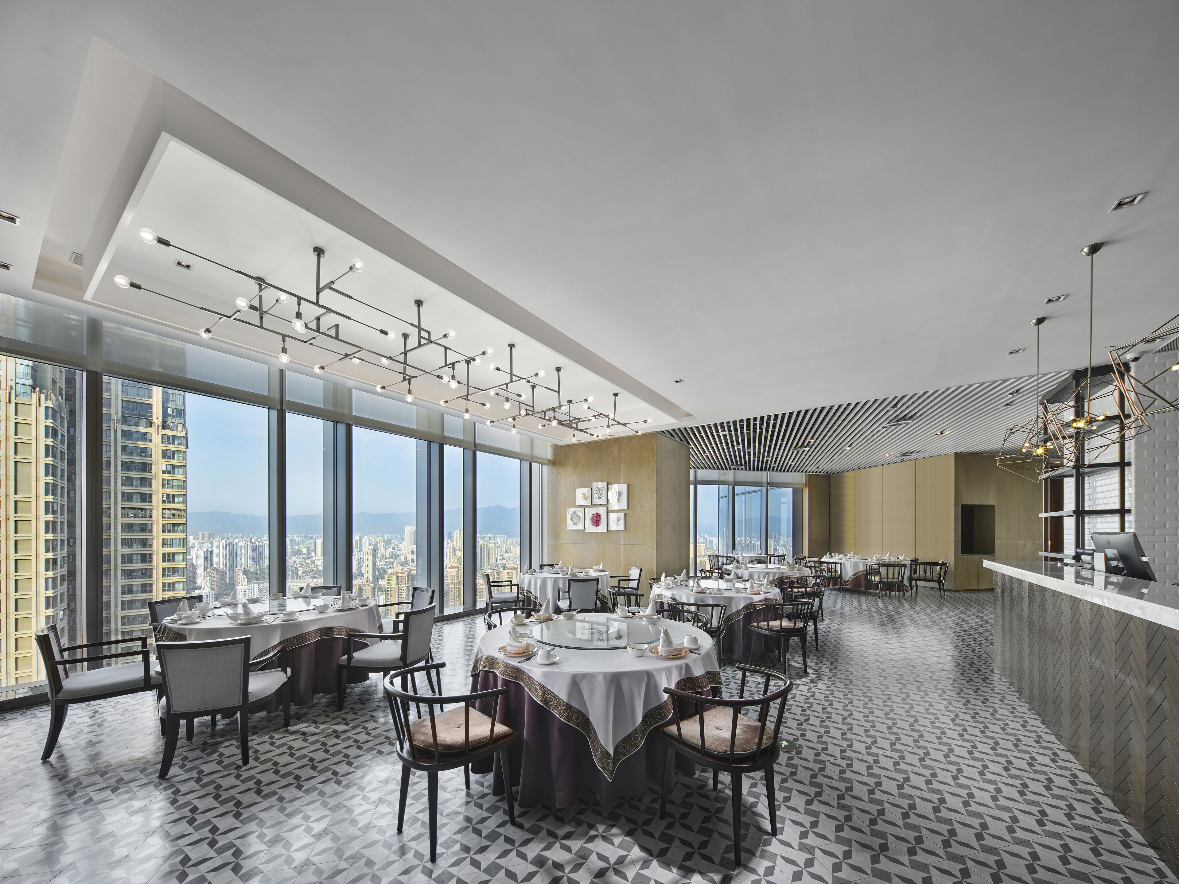 Un comedor moderno con techos altos, ventanas amplias y vistas a la ciudad.
