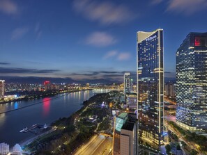 A high-rise hotel with a prominent 'Hilton' sign, surrounded by a river and other buildings. - Hilton Fuzhou (Fuzhou)