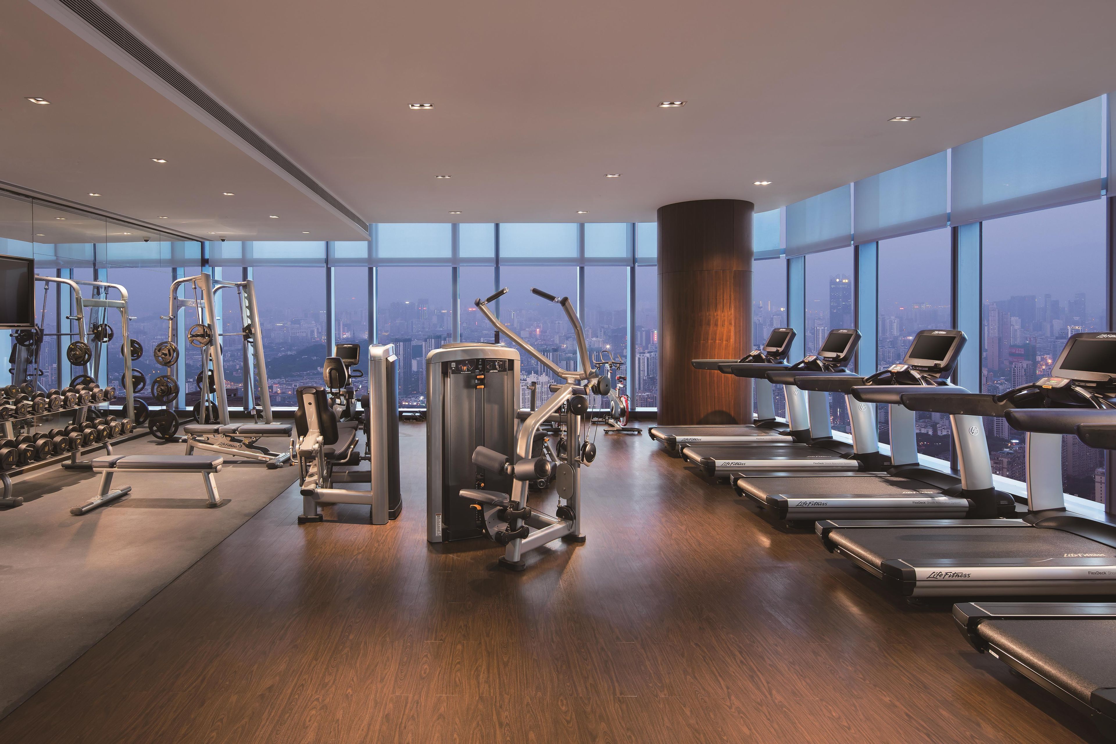 Un gimnasio con equipo cardiovascular, máquinas de pesas y mancuernas.
