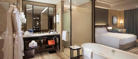 A modern hotel room with a large bed, a separate bathroom with a bathtub, a vanity with a mirror, and a large mirror reflecting the room.
