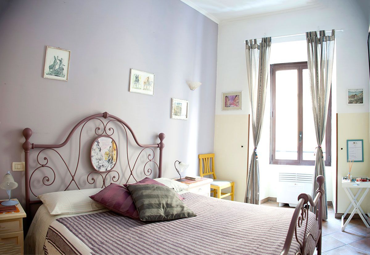 A neatly arranged bedroom with a bed, bedside table, lamp, and a window with curtains.