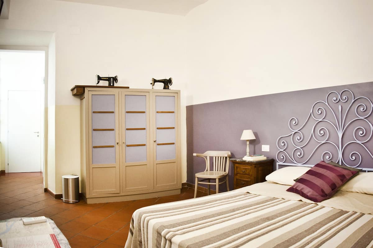 Um quarto com uma cama, guarda-roupa, cadeira e mesa de cabeceira.
