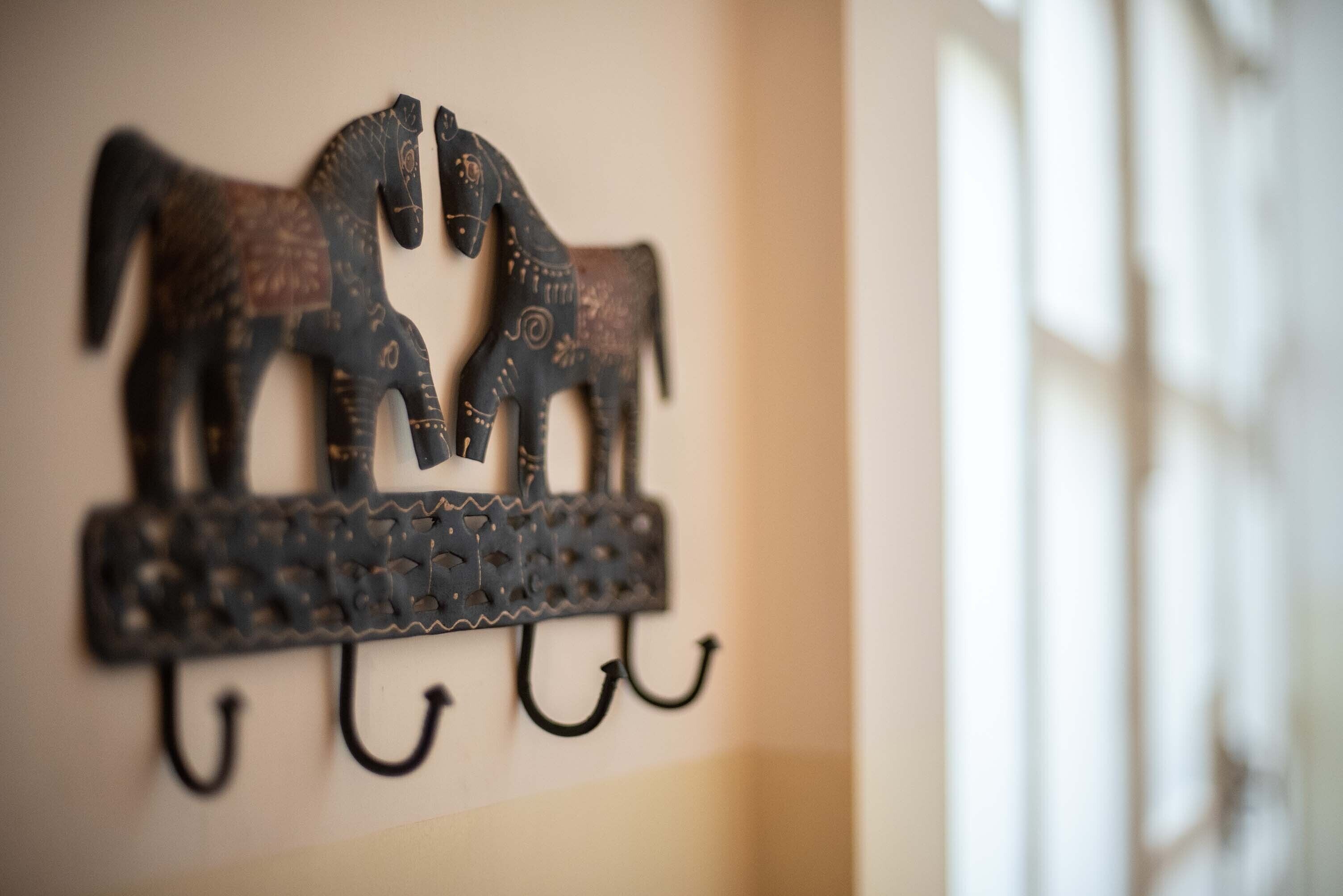A wall-mounted metal sculpture of two horses with a textured pattern.
