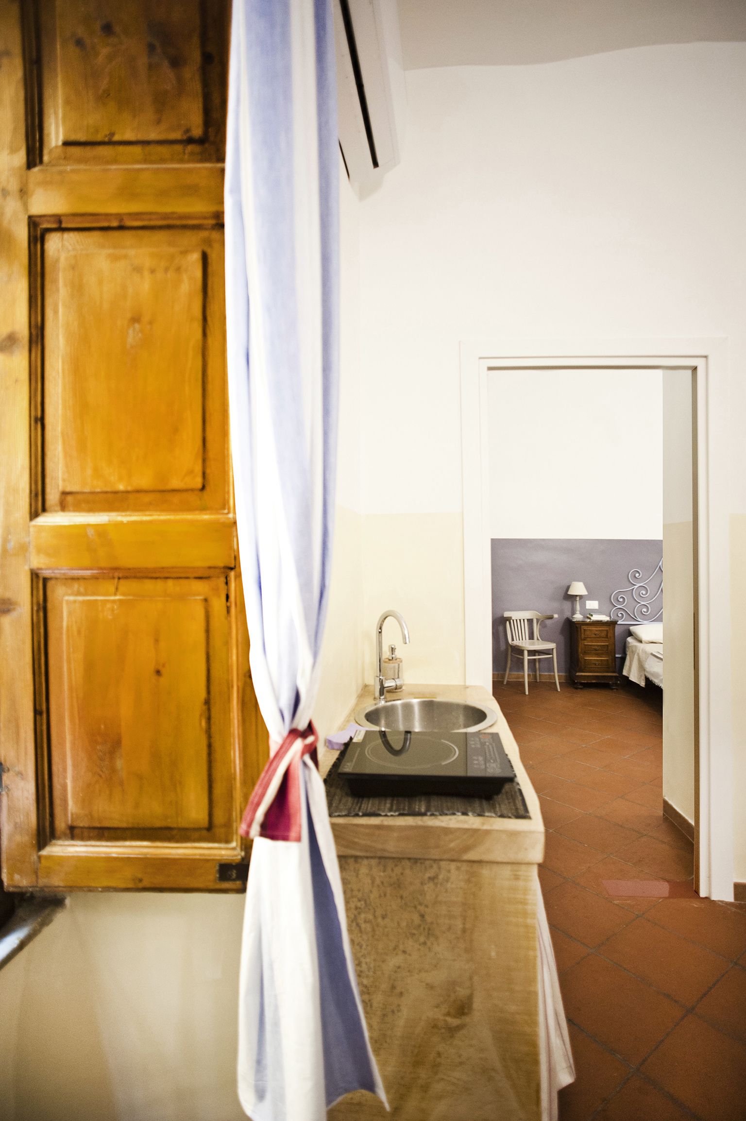 A kitchen with a sink, a wooden cabinet, and a chair.