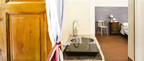 A kitchen with a sink, a wooden cabinet, and a chair.