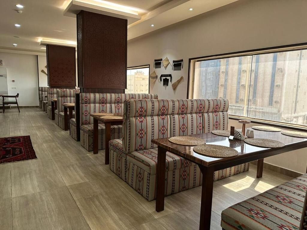 Un vestíbulo de hotel con zonas de estar, una mesa de madera y un ventanal grande.