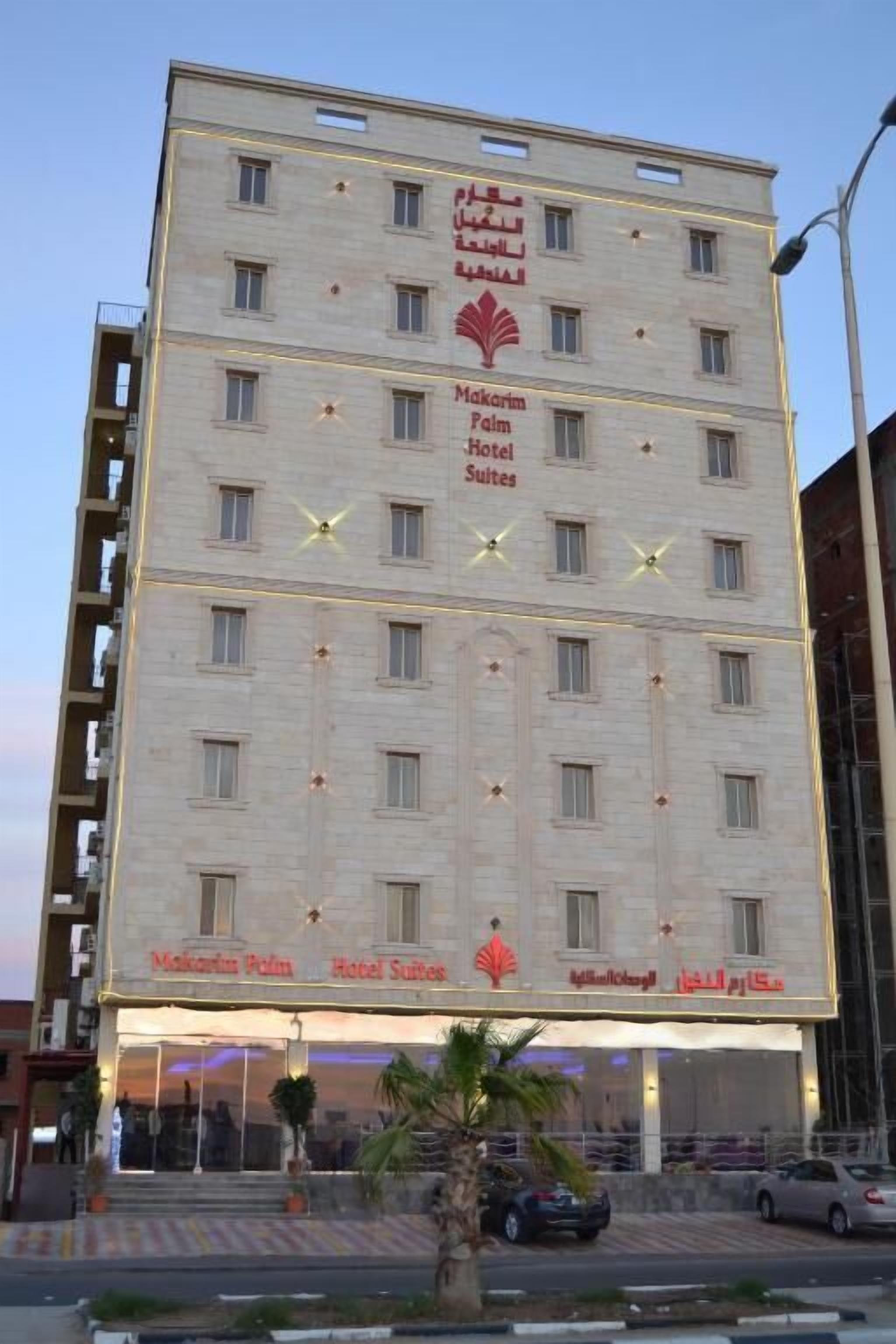 A multi-story hotel with a prominent palm tree logo and the name 'Makarin Palm Hotel Suites' displayed on the facade.