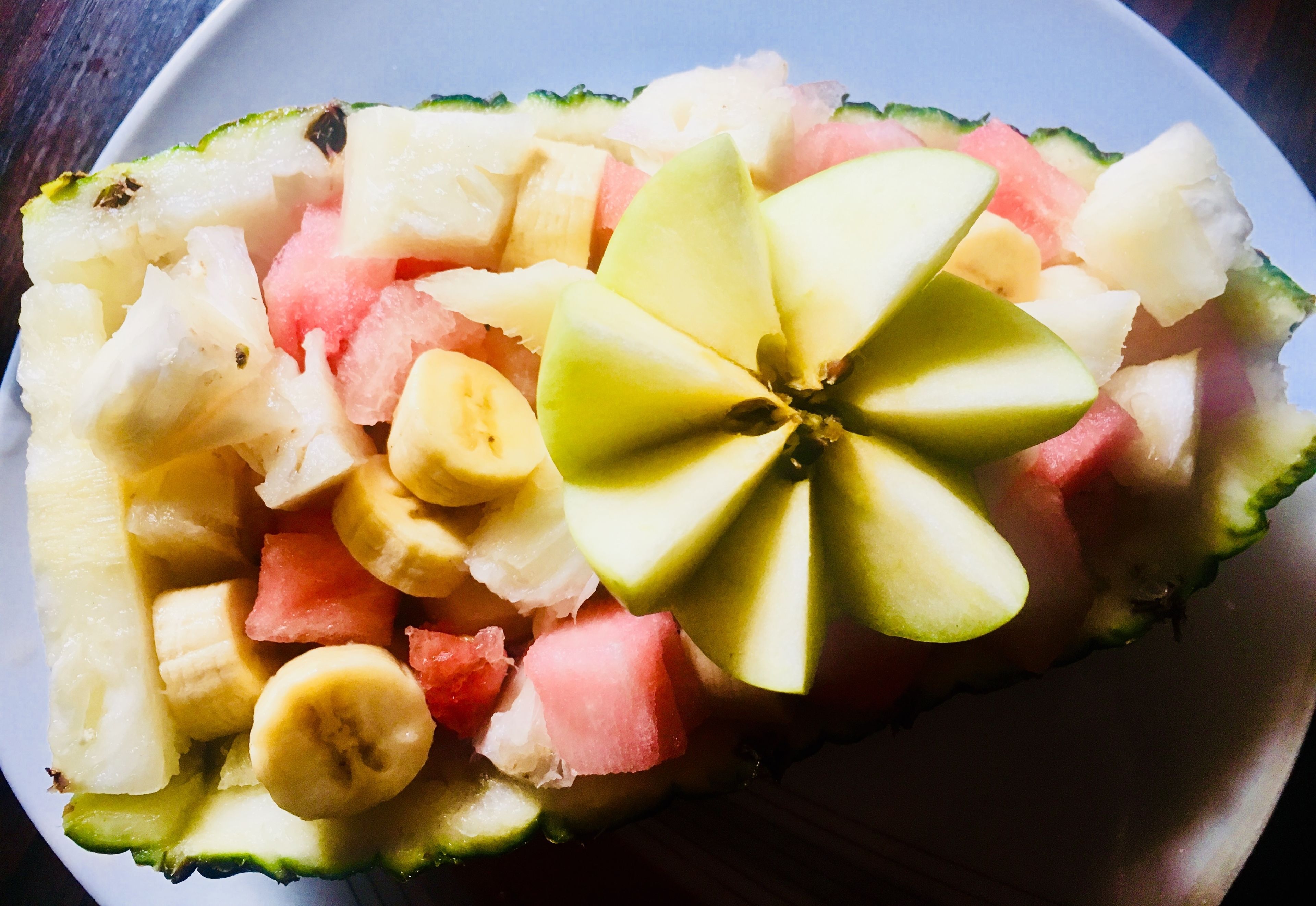 A bowl of fruit salad with various fruits including bananas, watermelon, and apple slices.