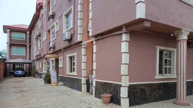 A multi-story building with a red facade, multiple windows, and a paved courtyard. - HardRock Hotel and suites (Lagos)