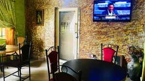 A room with a television mounted on the wall, a door with a sign, and a table with chairs. - HardRock Hotel and suites (Lagos)