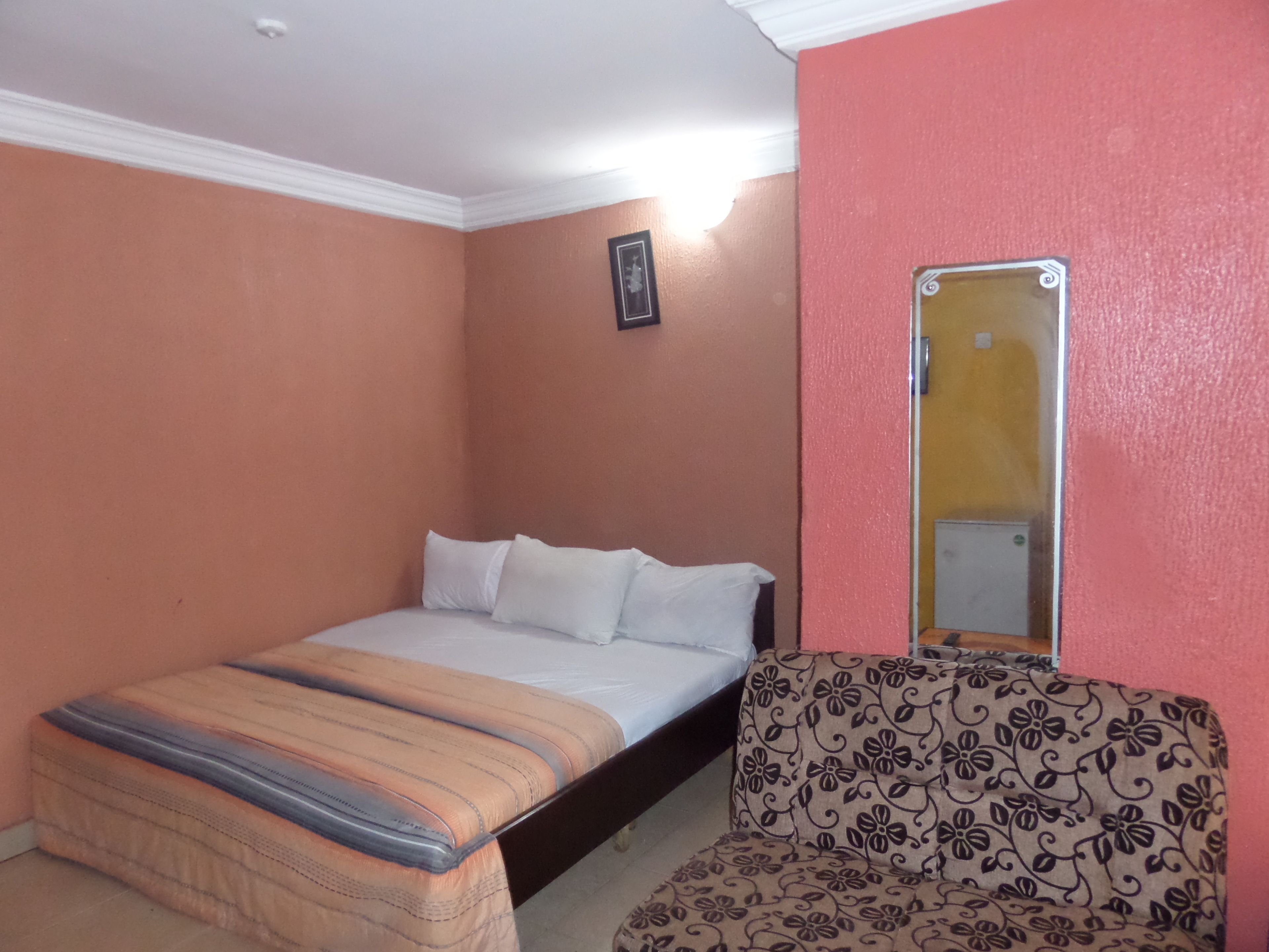 A bedroom with a bed, a chair, and a mirror.