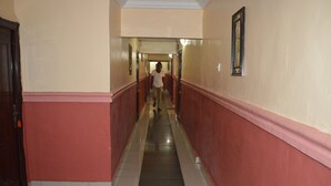 A long, narrow hallway with red and cream walls, a tiled floor, and a door at the end. - HardRock Hotel and suites (Lagos)