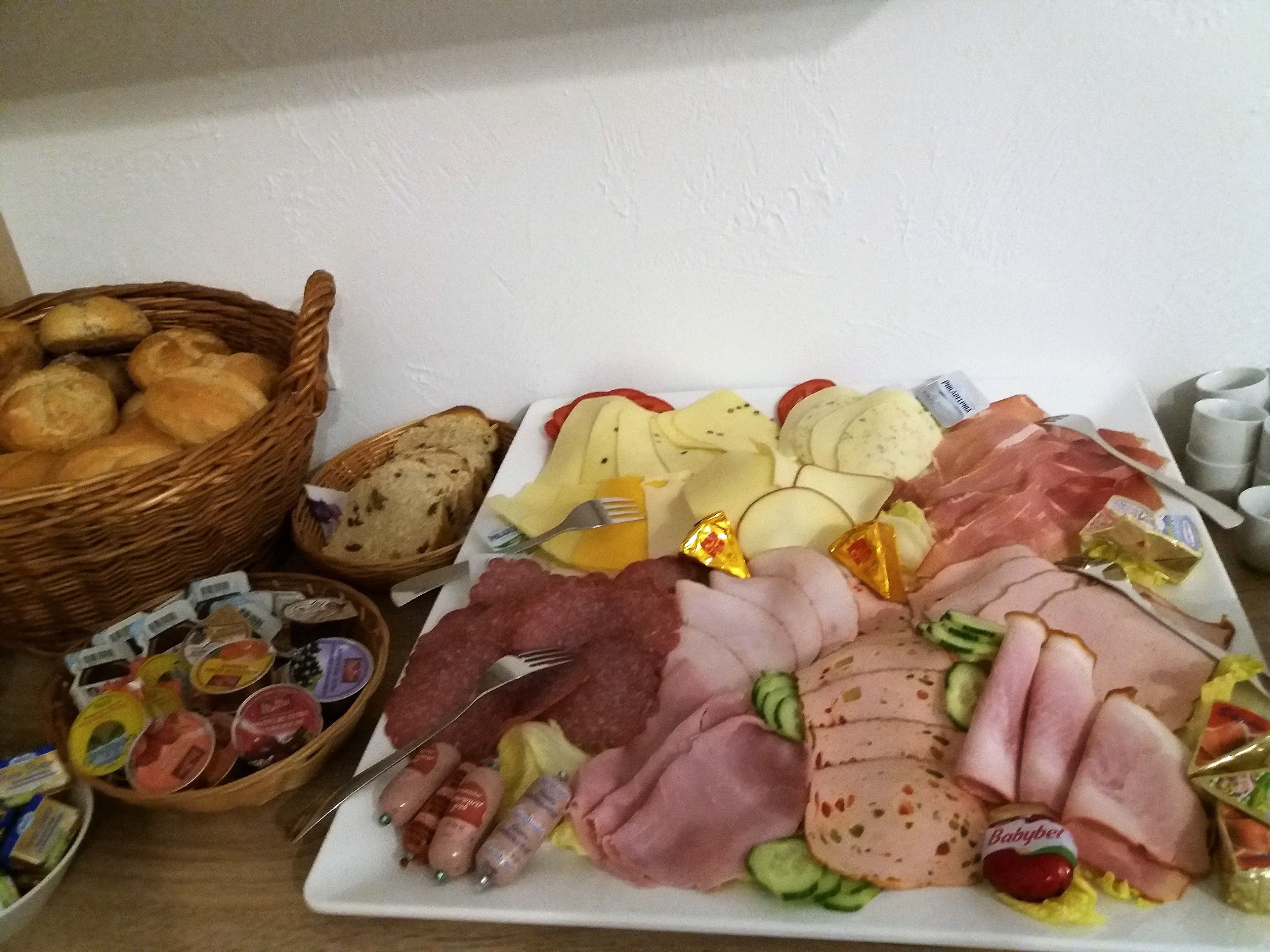 Una tabla de fiambres con diversos tipos de carne, quesos y panes.