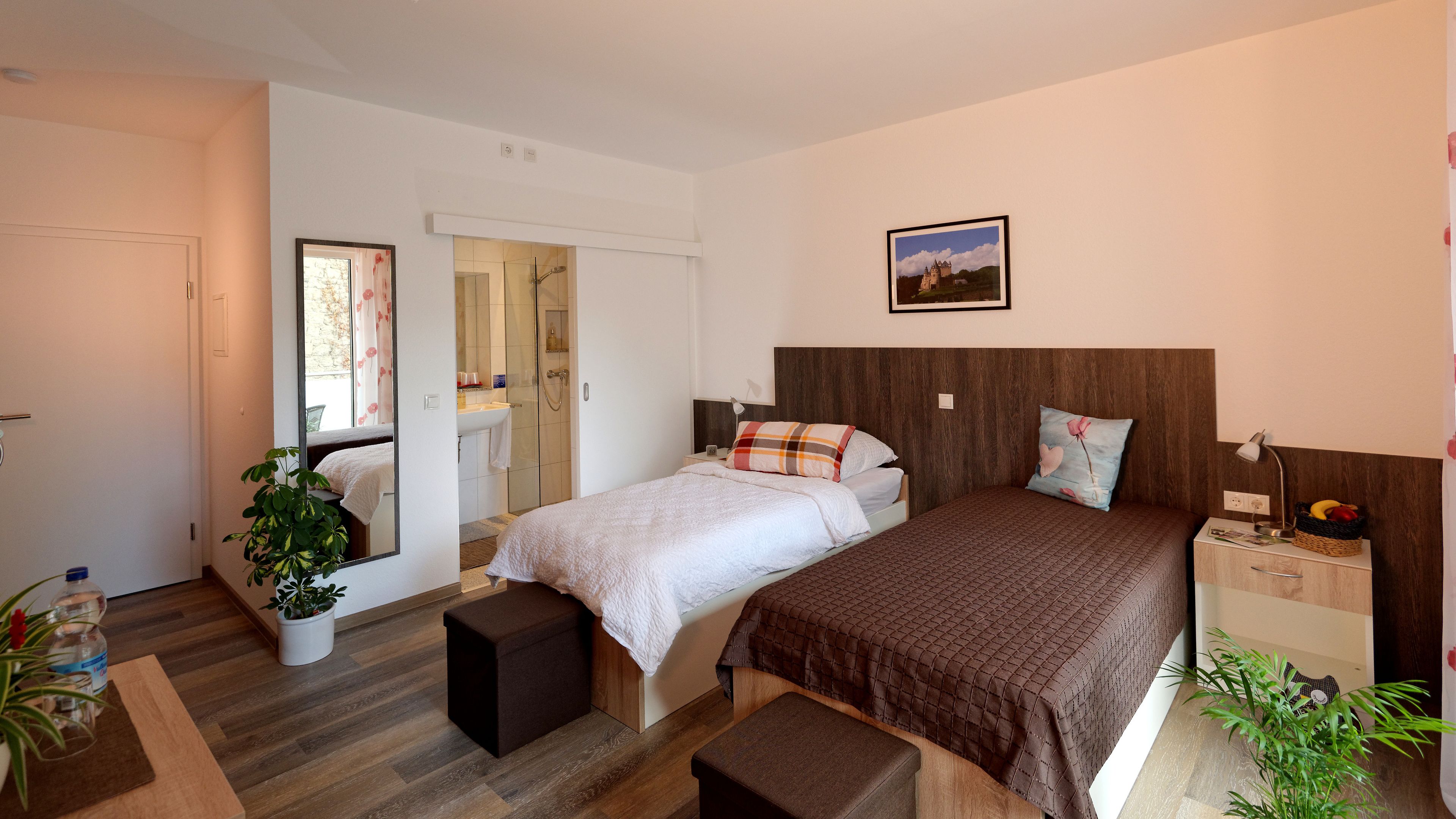 A bedroom with two beds, a bathroom, and a small table with a lamp.