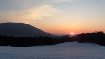 A snowy landscape with a sunset over a hill.
