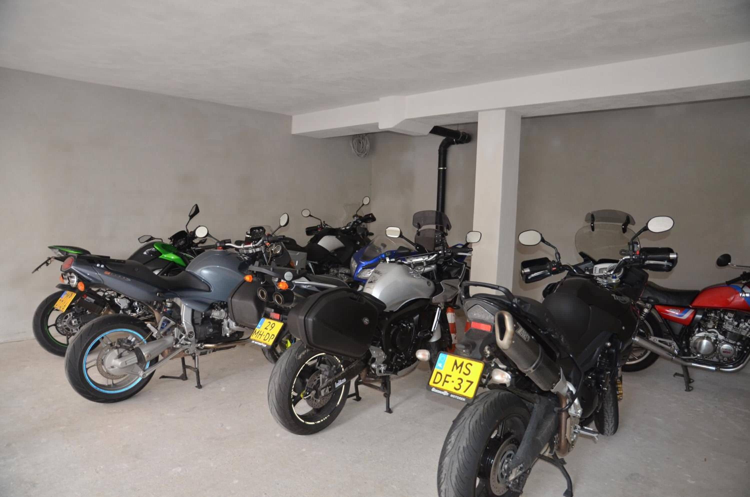 En parkeringsplads med flere motorcykler, hver med synlig nummerplade.