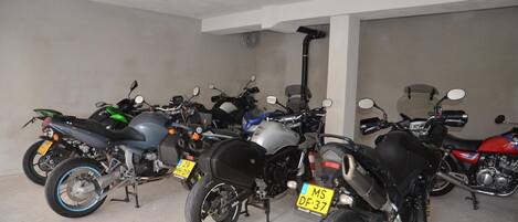 En parkeringsplads med flere motorcykler, hver med synlig nummerplade.