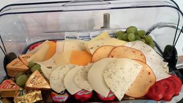 Una vitrina de vidrio con varios quesos, uvas y galletas.