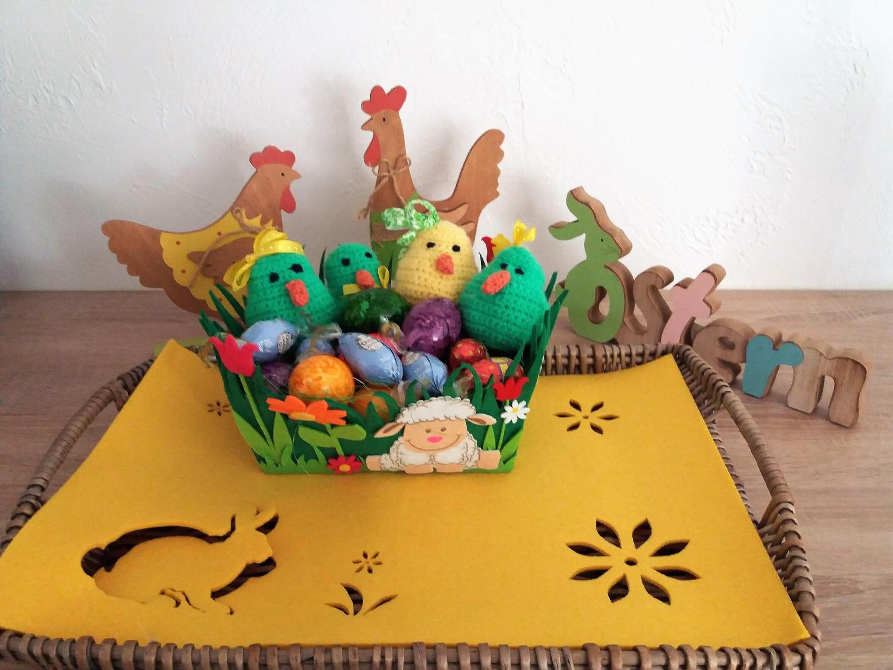 A basket filled with colorful Easter eggs and a small figurine of a lamb, placed on a yellow placemat with cut-out designs.