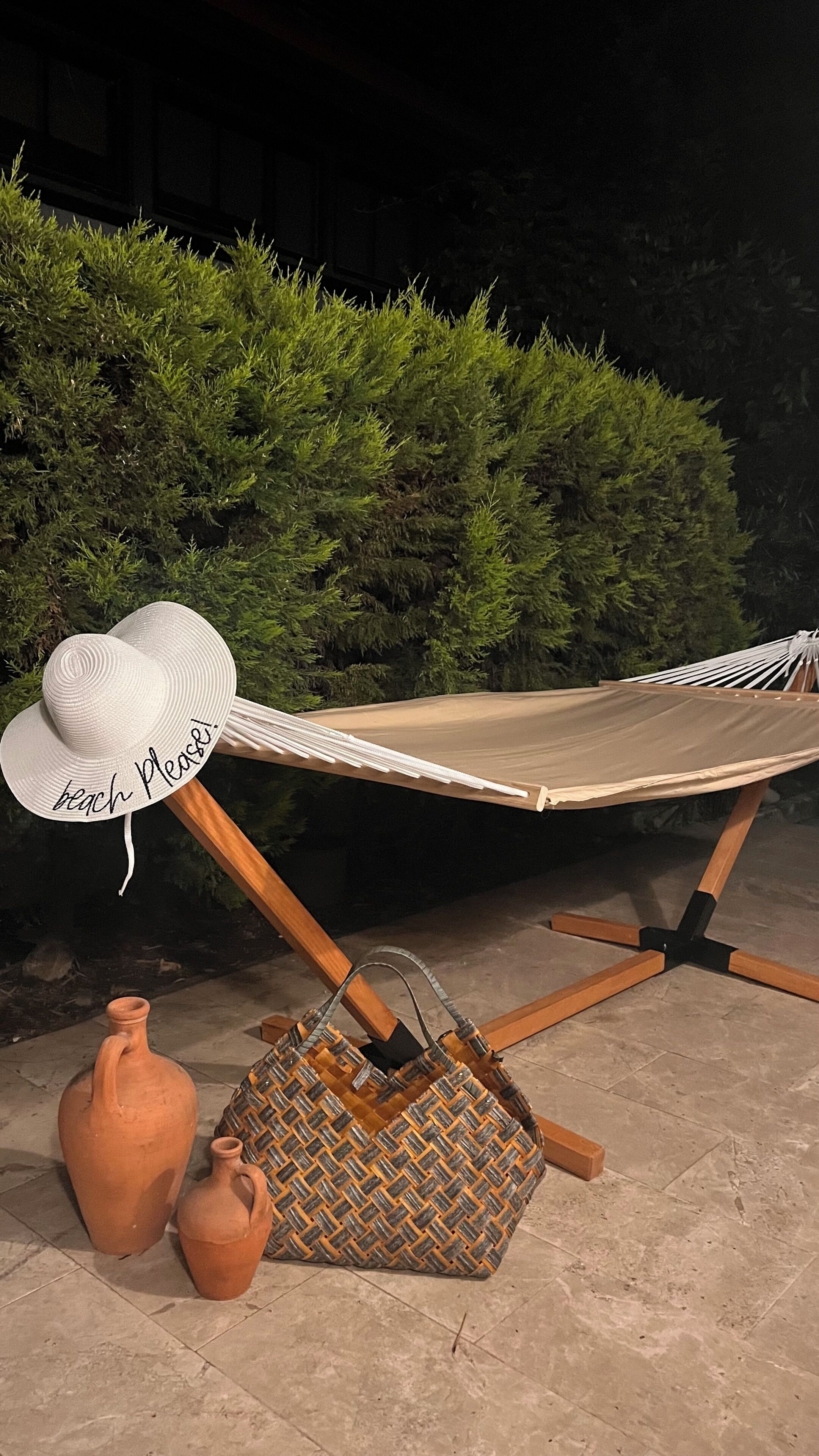 A hammock with a white hat on it, placed on a wooden stand.
