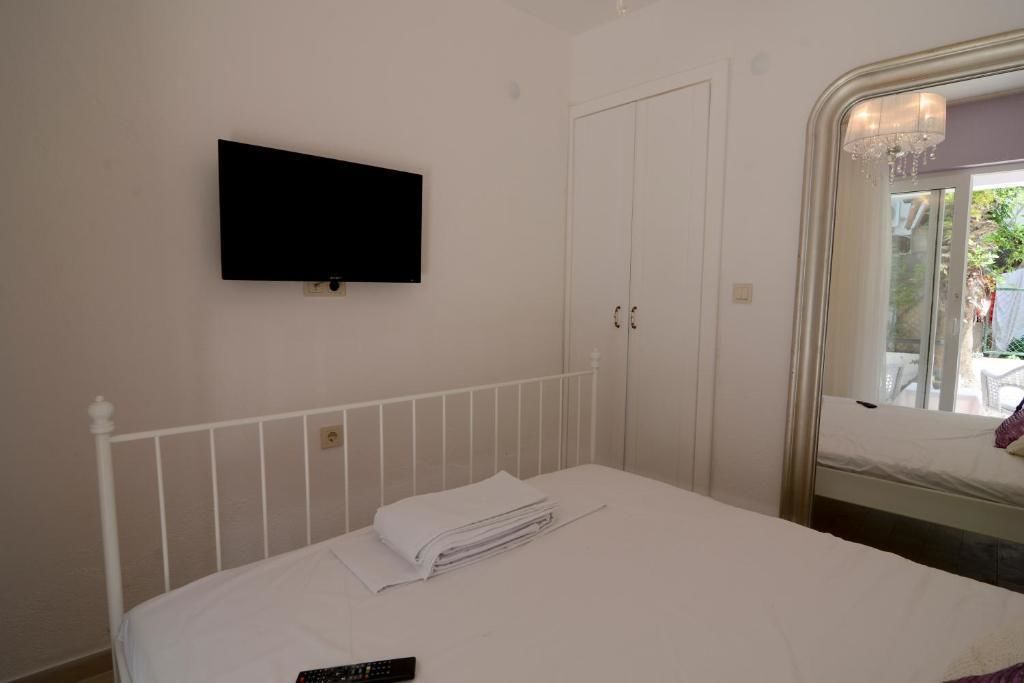 Un dormitorio con cama, televisor montado en la pared, armario y ventana con vista al exterior.