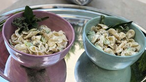 Dos ensaladas de pasta en un recipiente reflectante.
